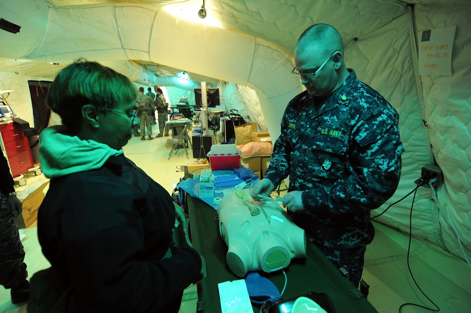 Senior clinician instructing trainees on a procedural skill during a hospital teaching round.